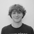 A young white man with curly hair smiles at the camera. 