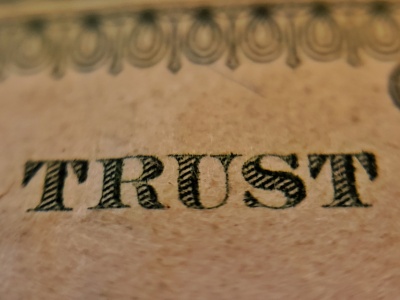 A close up of the word TRUST written in gothic serif font on a brown piece of paper.